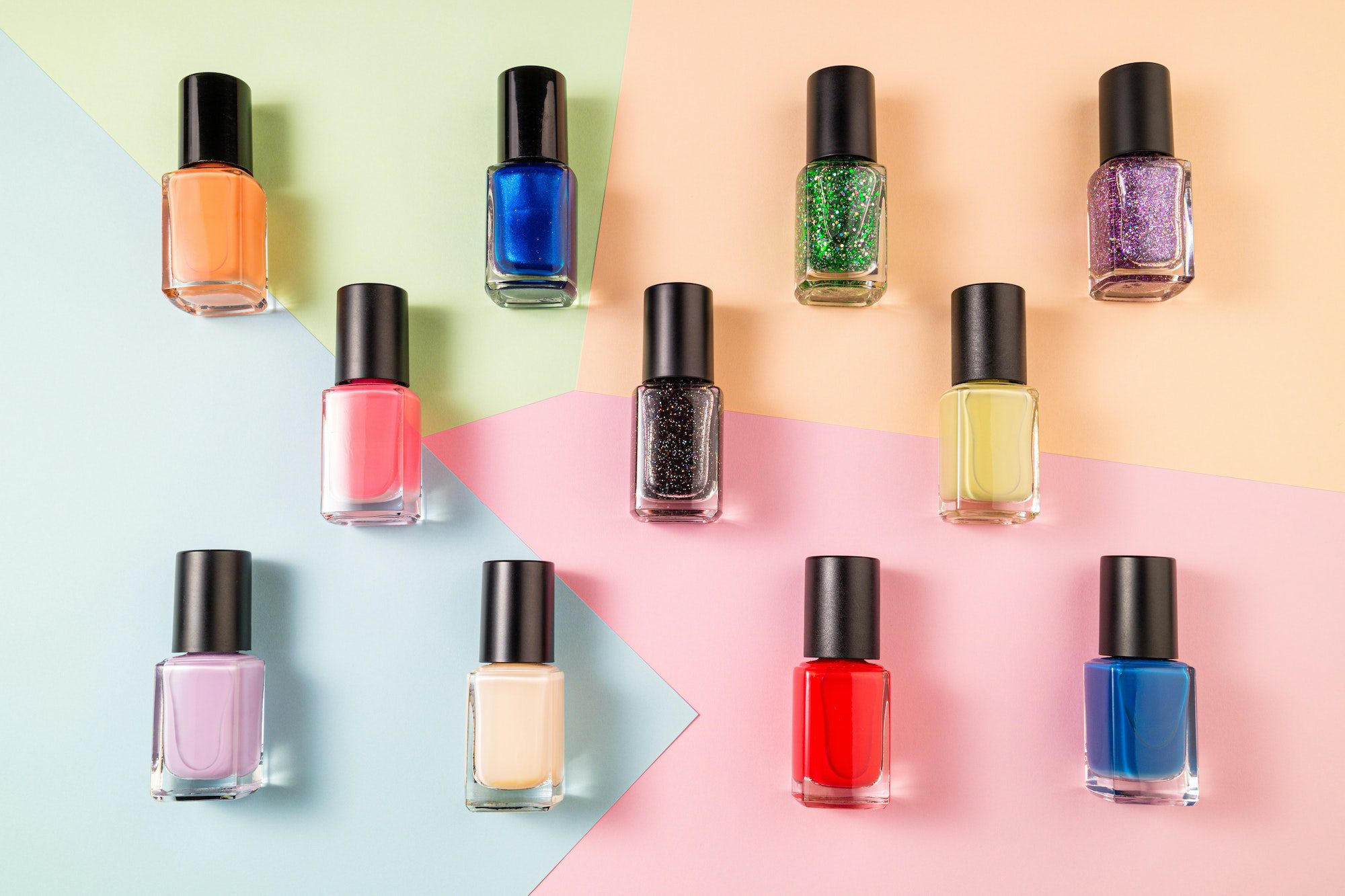 Pattern of various nail polish bottle on color background. Stylish trendy nail polish